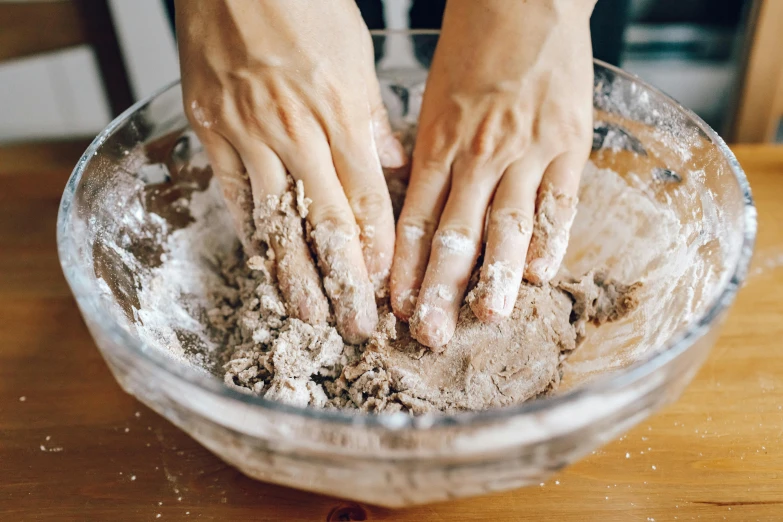 a close up of a person's hands in a bowl of food, a marble sculpture, by Julia Pishtar, trending on pexels, process art, baking cookies, messy brown hair, made of cement, ilustration