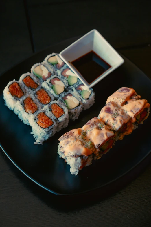 a black plate topped with sushi next to a bowl of sauce, blue or red, 🥥 🍕 hybrid, back to back, square