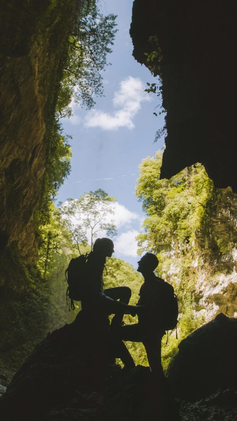 a couple of people that are standing in a cave, by Jessie Algie, pexels contest winner, as seen from the canopy, calmly conversing 8k, te pae, beautiful sunny day