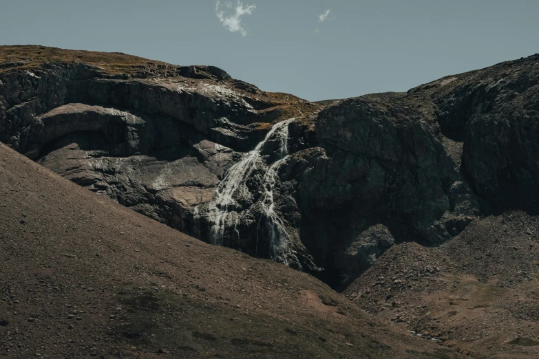 a man standing on top of a mountain next to a waterfall, les nabis, 4k detail post processing, rocks coming out of the ground, image from afar, lariennechan