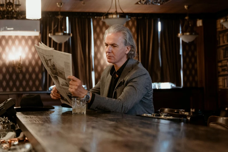 a man sitting at a bar reading a newspaper, pierce brosnan, quicksilver, shot with sony alpha, promotional image
