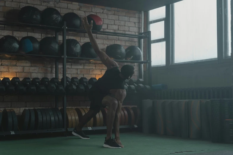 a man holding a medicine ball in a gym, by Emma Andijewska, pexels contest winner, hurufiyya, cinematic still frame, doing a kick, riyahd cassiem, low quality footage