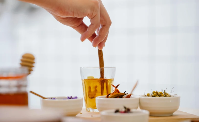 a person dipping a spoon into a bowl of food, inspired by Kanō Shōsenin, trending on pexels, process art, trapped in tall iced tea glass, dried herbs, test tubes, miniature cosmos