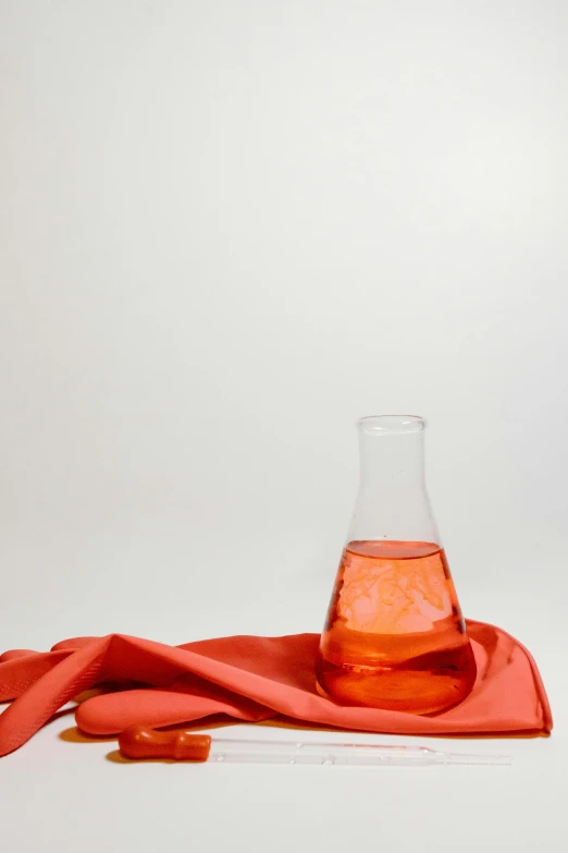 a bottle of liquid sitting on top of a red cloth, scientific glassware, orange safety vest, clean aesthetic, 9