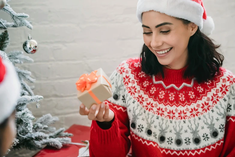 a woman in a santa hat holding a present, pexels contest winner, wearing casual sweater, avatar image, woman with black hair, entertaining