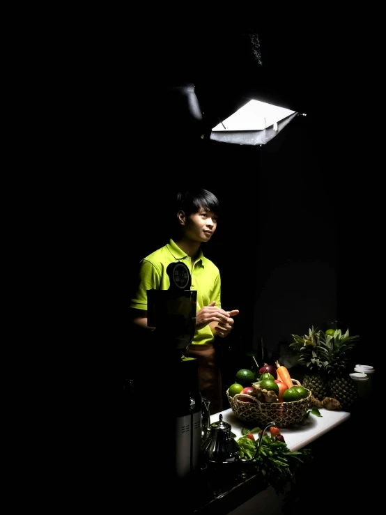 a man standing in front of a table filled with fruit, inspired by Joong Keun Lee, unsplash, studio!! portrait lighting, cooking show, under a spotlight, side light