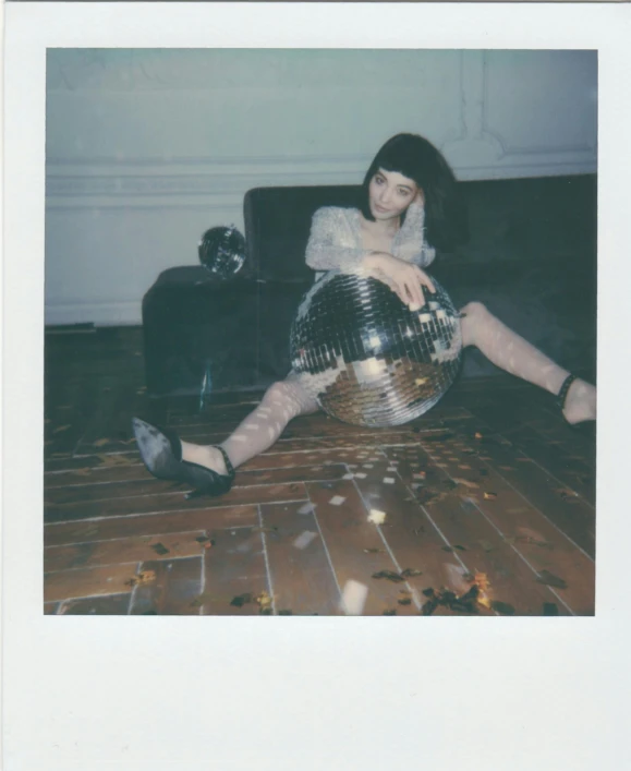 a woman sitting on the floor with a disco ball, a polaroid photo, inspired by Elsa Bleda, holography, straight bangs, discogs, belle delphine, medium format