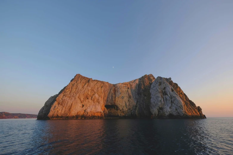 a large rock in the middle of a body of water, a digital rendering, pexels contest winner, romanticism, cliff side at dusk, piroca, photo taken from a boat, slide show