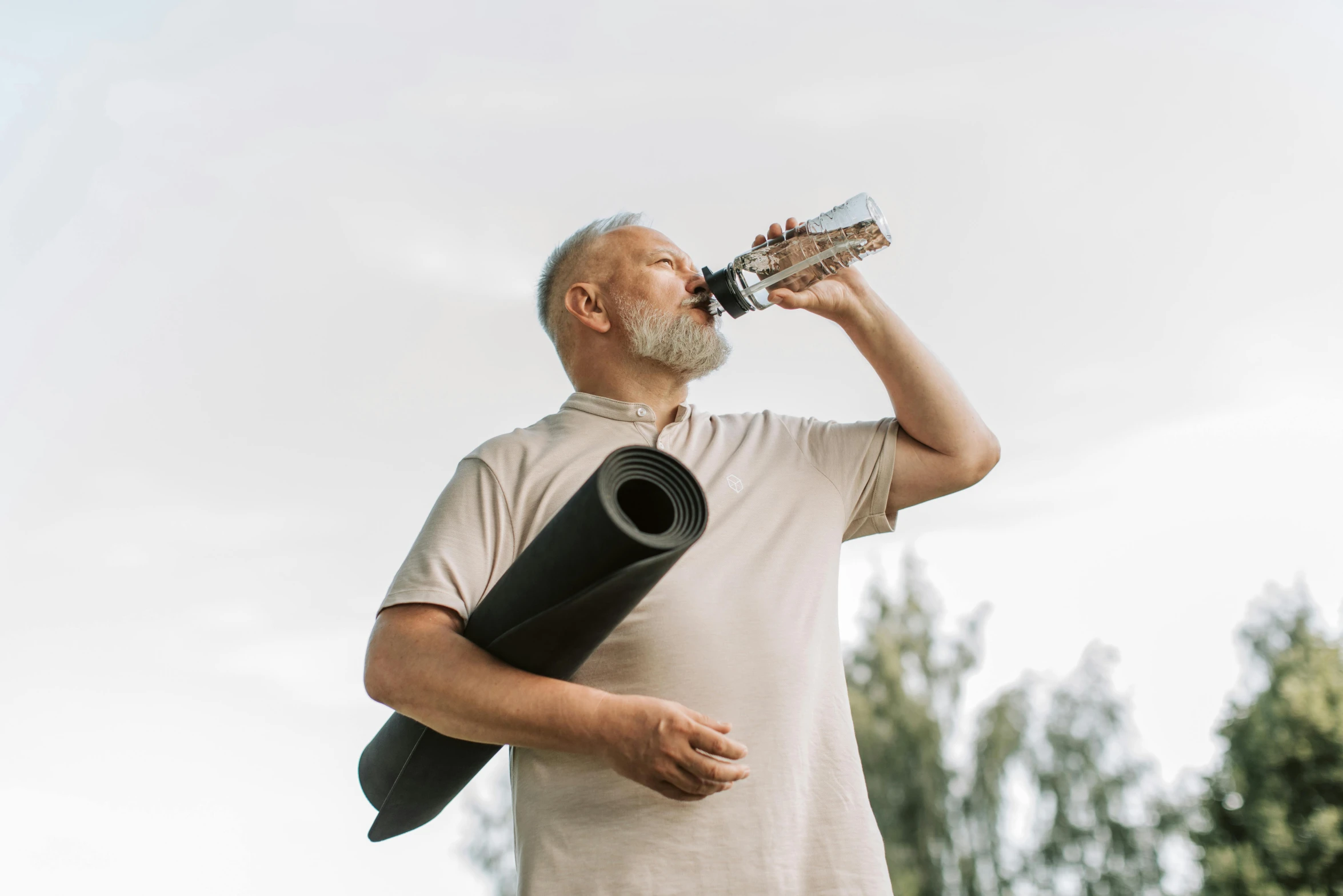 a man drinking water from a bottle while holding a yoga mat, pexels contest winner, happening, old gigachad with grey beard, profile image, brown, black