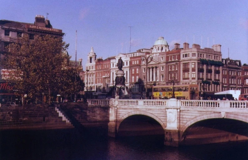 a bridge over a river with buildings in the background, by Frank O'Meara, flickr, renaissance, on a great neoclassical square, vhs colour photography, irish, statue