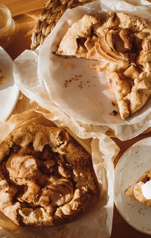 a wooden table topped with plates of food, a still life, by Lee Loughridge, unsplash, renaissance, apple pie, parchment paper, thumbnail, crackles