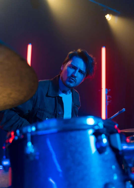 a man that is sitting in front of a drum, cinematic blue lighting, mark edward fischbach, profile image, thumbnail