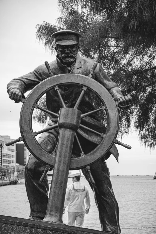 a statue of a man holding a steering wheel, a statue, on the bow, 1982, stern face, from waist up