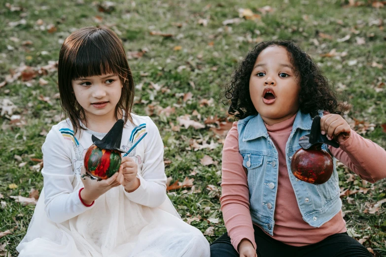 a couple of young girls sitting on top of a lush green field, inspired by Lucas Cranach the Elder, pexels contest winner, decorated ornaments, happy meal toy, holding an apple, four years old