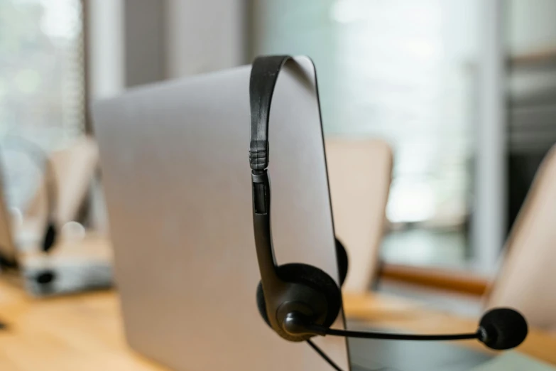 a laptop computer sitting on top of a wooden desk, headset, thumbnail, grayish, sitting across the room