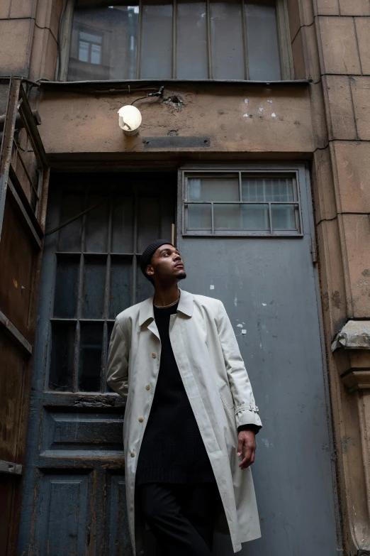 a man standing in front of a building, an album cover, pexels contest winner, wearing a long beige trench coat, ( ( theatrical ) ), location [ chicago ( alley ) ], felix kelly