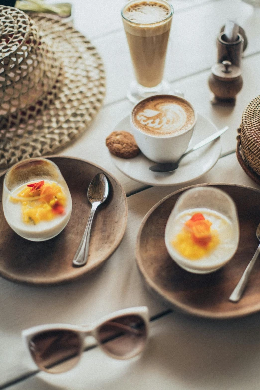 a table topped with plates of food next to a cup of coffee, mango, cream, bali, translucent eggs