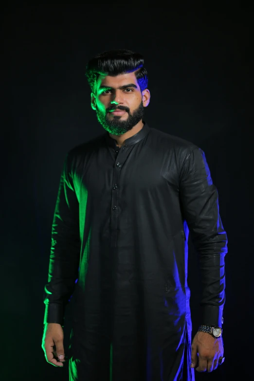 a man standing in front of a green light, an album cover, inspired by Osman Hamdi Bey, pexels contest winner, black shirt, candid!! dark background, wearing a kurta, professional modeling