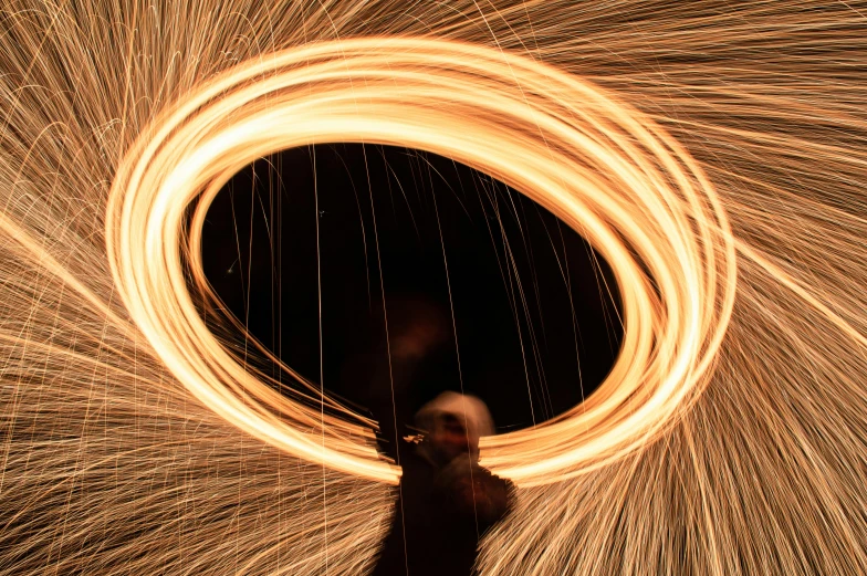 a person standing in front of a circular light painting, pexels contest winner, kinetic art, blacksmith, ring flash closeup photograph, brown, steel wire