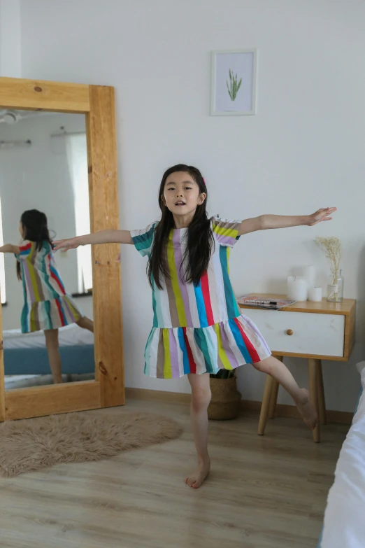 a little girl standing in front of a mirror, inspired by Ni Yuanlu, happening, arms stretched out, at home, ( ( theatrical ) ), multicoloured