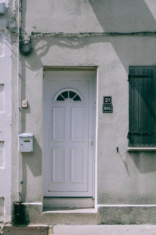 a white door sitting on the side of a building, by Sven Erixson, unsplash, french village exterior, 90's photo, multiple stories, front