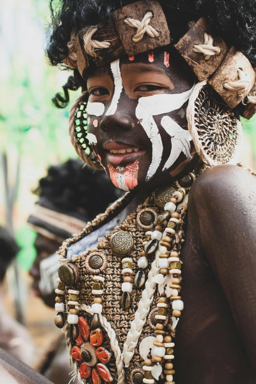 a close up of a person with a painted face, by Daniel Lieske, pexels contest winner, afrofuturism, wearing an elegant tribal outfit, kids, tribe members chasing, lush surroundings