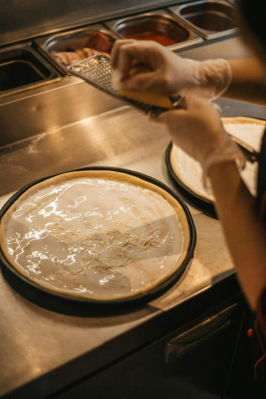 a person in a kitchen making a pizza, a silk screen, by Robbie Trevino, trending on unsplash, gold gilded circle halo, dessert, closeup - view, high-quality photo
