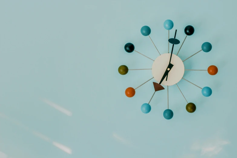 a clock sitting on top of a blue wall, by Doug Ohlson, trending on pexels, kinetic art, colored dots, newton's cradle, mid-century modern, vintage - w 1 0 2 4