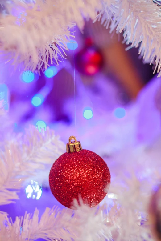 a red ornament hanging from a white christmas tree, by Julia Pishtar, red and blue lighting, soft lights, medium detail, promo image