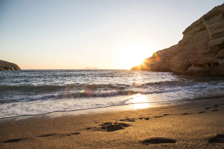 footprints in the sand on a beach at sunset, pexels contest winner, costa blanca, sparkling cove, thumbnail, cliffs