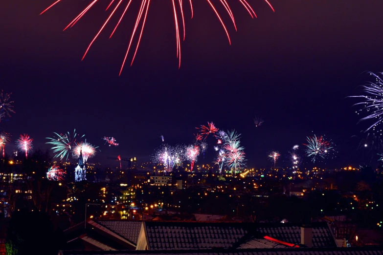 fireworks light up the night sky over a city, a photo, by Julia Pishtar, shot from roofline, holiday season, background image, multiple stories