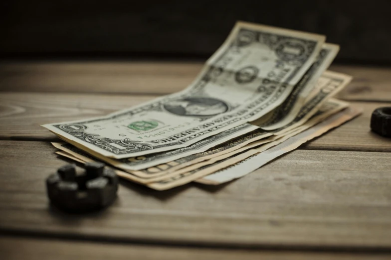 a pile of money sitting on top of a wooden table, a portrait, unsplash, vintage photo, fan favorite, modeled, slide show