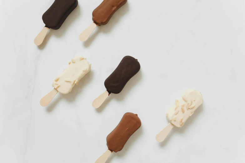 a group of ice cream pops sitting on top of a counter, by Emma Andijewska, dark sienna and white, 6 pack, chocolate, thumbnail