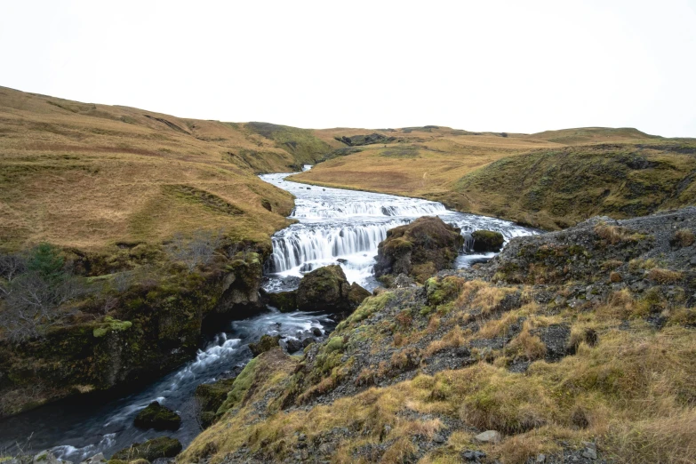 a river flowing through a lush green hillside, by Hallsteinn Sigurðsson, unsplash, hurufiyya, frozen waterfall, taken on iphone 14 pro, 2 0 0 0's photo, mid fall