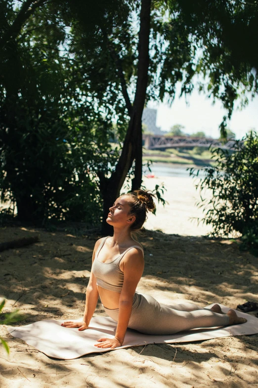 a woman is doing a yoga pose on the beach, by Adam Marczyński, unsplash, renaissance, near a river, in sunny weather, in a city park, porcelain skin ”