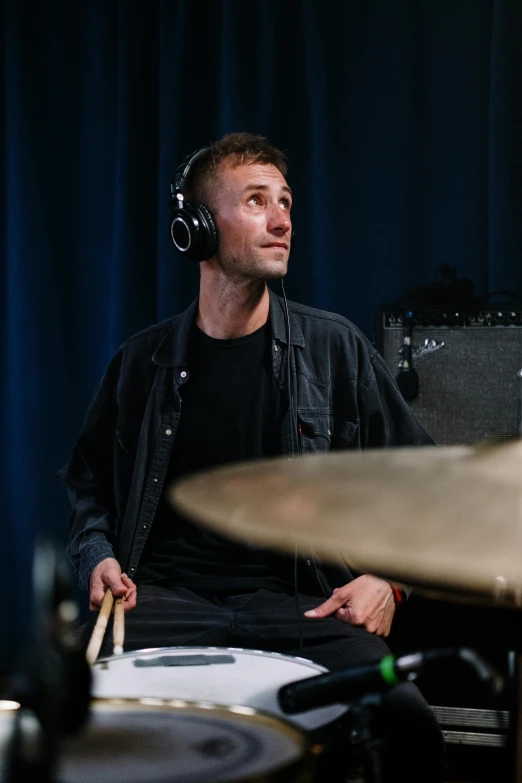 a man sitting in front of a drum set, liam brazier, with head phones, sydney hanson, solid background