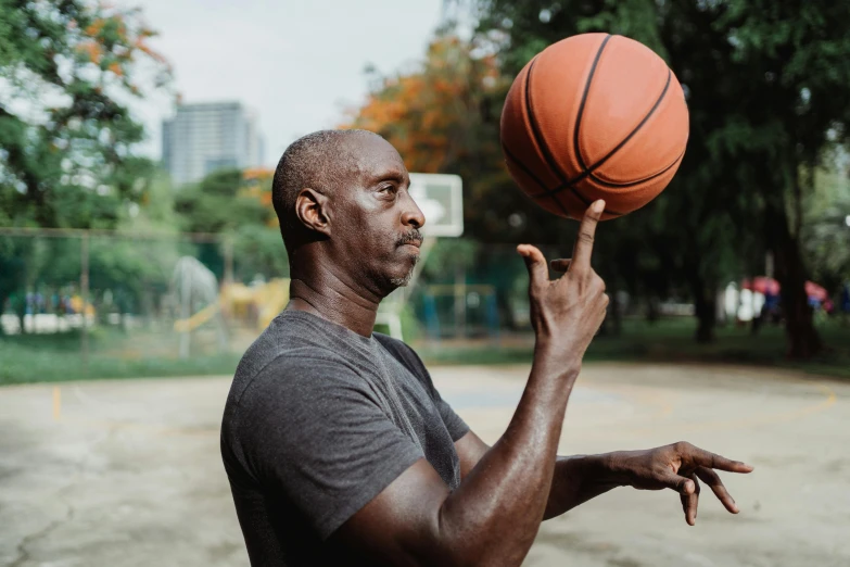 a man spinning a basketball on his finger, inspired by Paul Georges, pexels contest winner, lance reddick, aged 4 0, profile image, holding a football