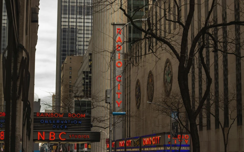 a crowd of people walking down a street next to tall buildings, a photo, by Dan Frazier, pexels contest winner, art nouveau, bright signage, [ theatrical ], red - yellow - blue building, broadway