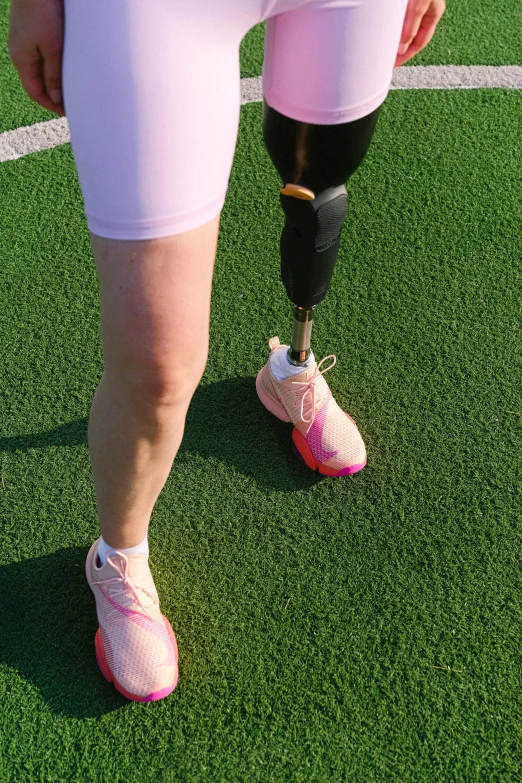 a woman with a prosthetic knee standing on a soccer field, by Matt Cavotta, dribble, low quality photo, pink, square, exoskeletton