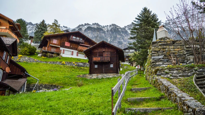 a couple of wooden buildings sitting on top of a lush green hillside, by Dietmar Damerau, pexels, lauterbrunnen valley, overcast mood, 💋 💄 👠 👗, well worn