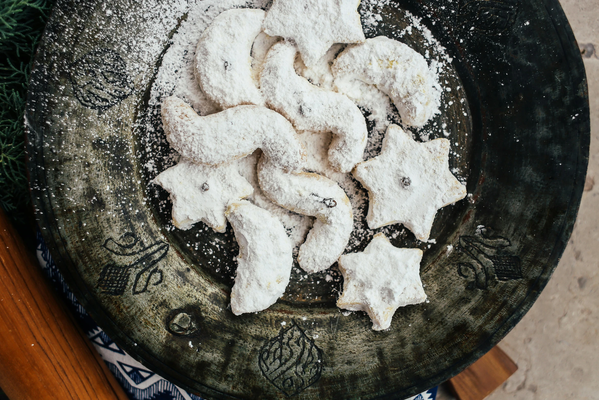 a black plate topped with cookies covered in powdered sugar, a stipple, inspired by Ödön Márffy, trending on pexels, arabesque, crescent moon, 2000s photo, mediterranean, made out of shiny white metal