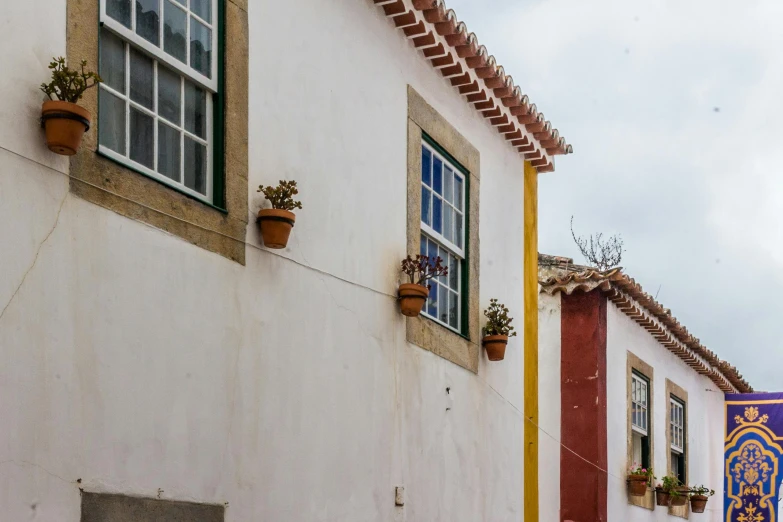 a clock that is on the side of a building, inspired by Ceferí Olivé, pexels contest winner, cloisonnism, several cottages, white walls, profile image, nazare (portugal)