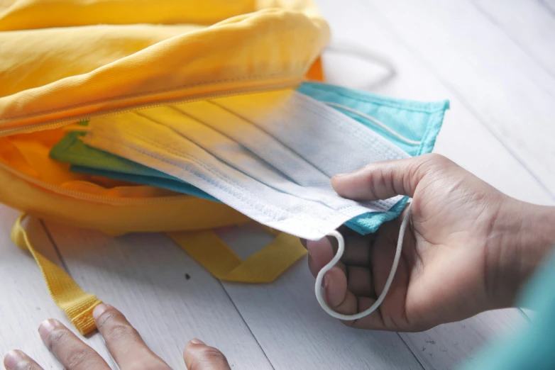 a close up of a person holding a pair of scissors, by Alice Mason, plasticien, face mask, school bag, with yellow cloths, thumbnail