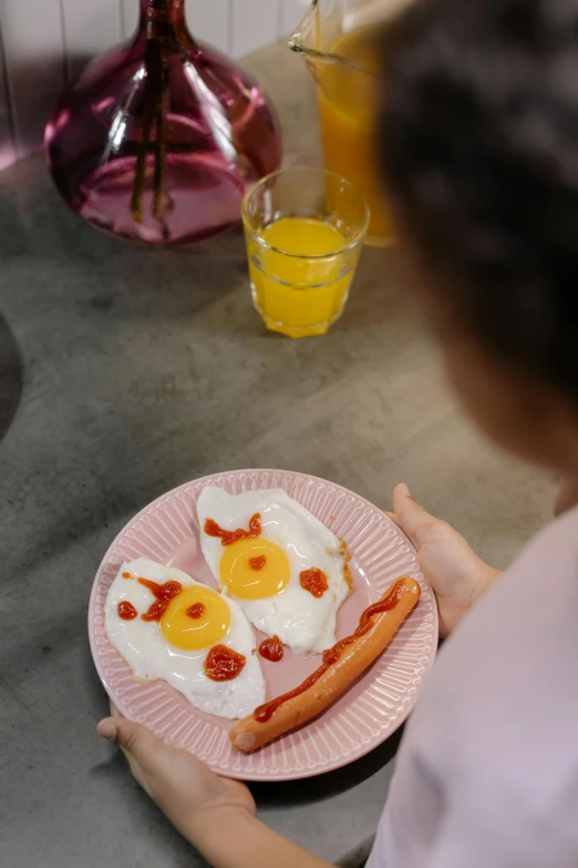 a person sitting at a table with a plate of food, eggs, hot dog, on a plate, up-close