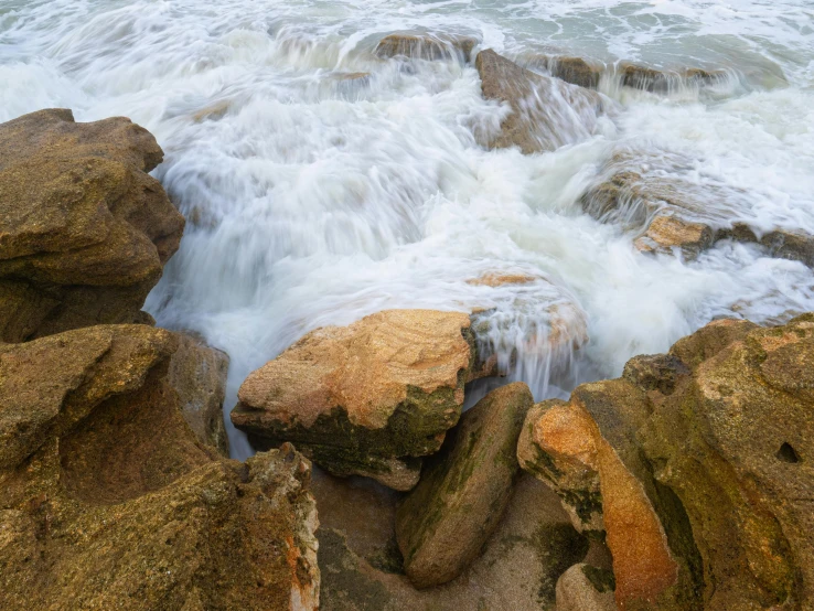 a group of rocks sitting on top of a body of water, crashing waves and sea foam, sandstone, gigapixel photo, 4k image