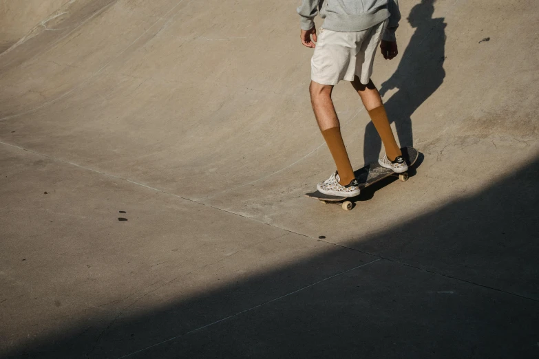 a man riding a skateboard up the side of a ramp, unsplash contest winner, hyperrealism, tan shorts, smooth shadows, wearing skirt and high socks, gradient brown to white