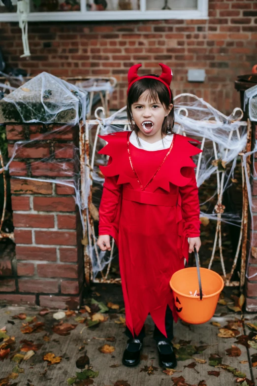 a little girl in a red dress holding a bucket, pexels contest winner, happening, with hellish devil wings, the gruffalo, trick or treat, red jumpsuit