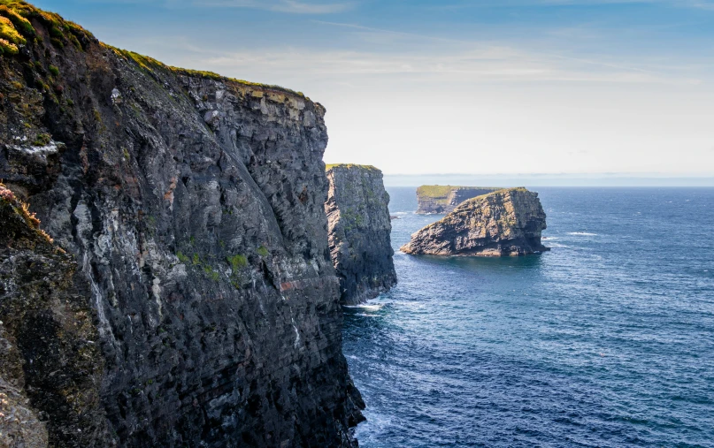 a man standing on top of a cliff next to the ocean, les nabis, mighty nein, rock arches, distant photo