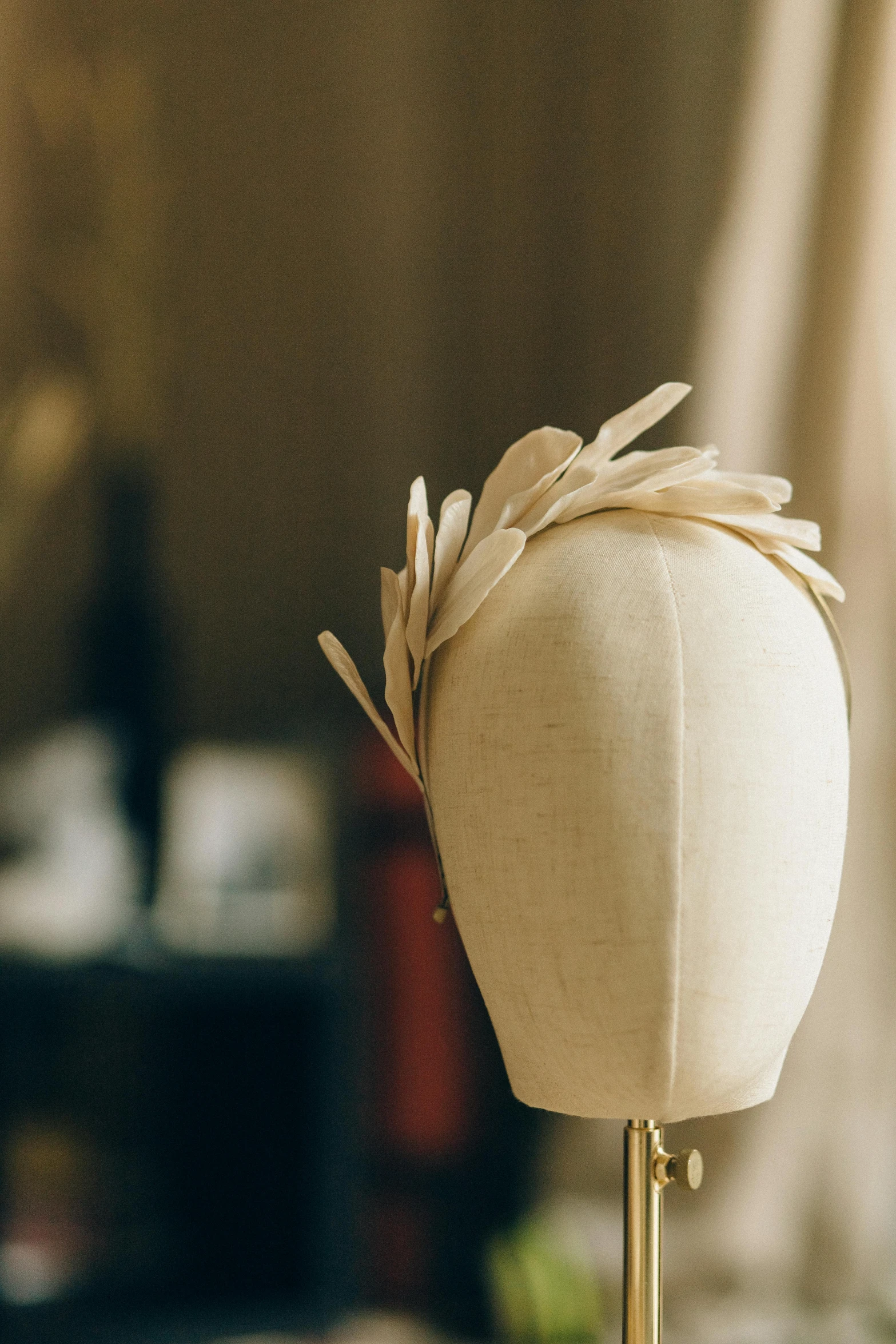 a mannequin head sitting on top of a table, small quills along it's back, crown made of fabric, bespoke, smooth oval head