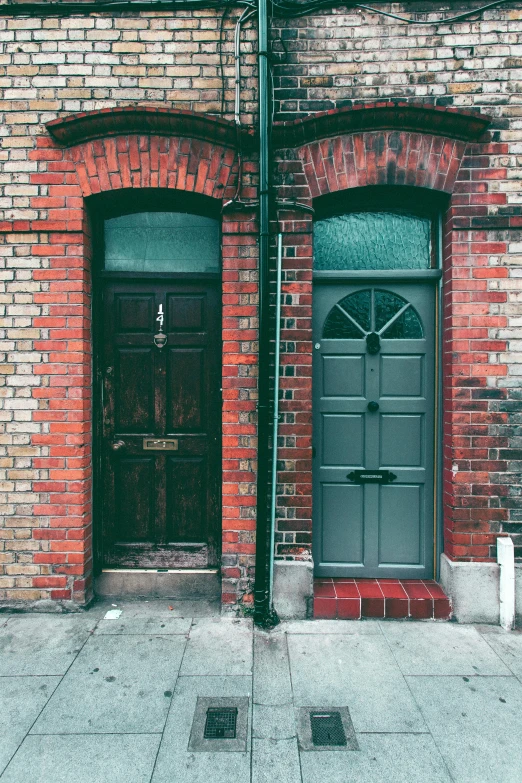 a couple of doors that are on the side of a building, a photo, unsplash, arts and crafts movement, dingy city street, bricks, interior of a victorian house, 1990s photograph